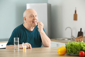 Elderly man taking medicine at home