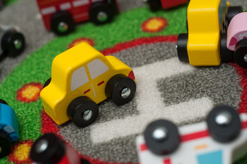 Fototapeta premium Closeup of miniature wooden cars on road carpet on the floor