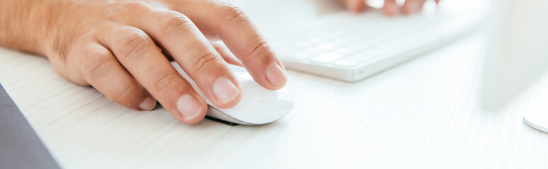 panoramic shot of broker using computer mouse near computer keyboard