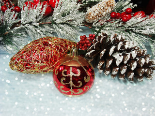 christmas ball on fir tree branch with cones and snow on background