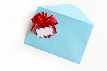 Blank paper blue envelope with red ribbon bow, letter for mail on white background, flat lay, top view. Concept postal service or greeting card