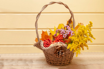Fototapeta na wymiar Autumn bouquet in a basket on a background of yellow wall