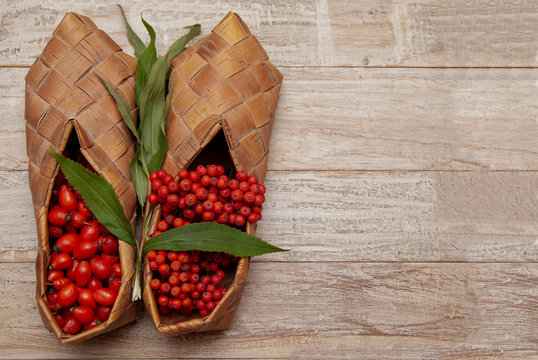 Rosehip berries and bunches of mountain ash in bast shoes are on the table.
