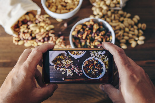 food blogger takes photo of varied nuts with phone