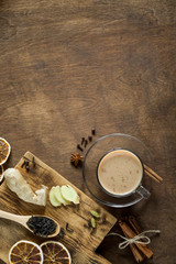 Masala tea in glass on wooden background in rustic style. Traditional Indian hot drink with milk, black tea and spices. Copy space, top view, close-up
