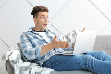 Shocked young man with laptop at home