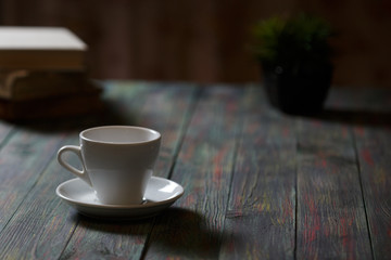 A cup of coffee in the workplace on a wooden table.