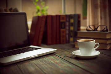 A cup of coffee in the workplace on a wooden table.