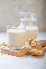 The concept of a vegetarian diet. Oat milk in the glass with jug of milk and oat.  Light background