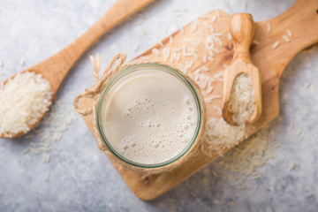 The concept of a vegetarian diet. Rice milk in the glass with rice grains . Light background
