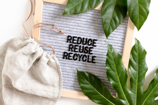 Green leaves, canvas bag and letterboard with quote Reduce Reuse Recycle. Zero waste concept