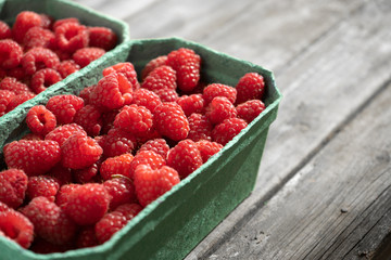 Fresh red raspberries in craft stalls, containers. on a wooden rustic old background. Top view of ripe berries. Autumn harvest.
