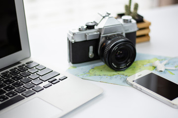 Desk with a notebook, telephone, camera, map, and planning a trip on white background with copy space