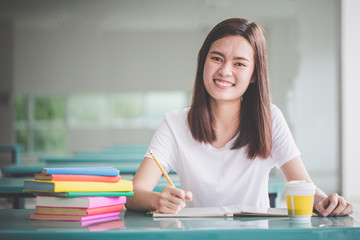 Education concept - Smiling university students are happy to read the exam books on the table.