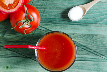 Tomato juice, tomatoes and salt on wooden background top view