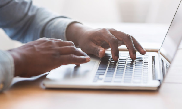 Unrecognizable african american man typing on laptop keyboard in office