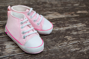 Fototapeta na wymiar Baby girl pink shoes on wooden background