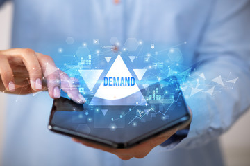 Businessman holding a foldable smartphone with DEMAND inscription, business concept
