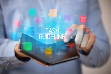 Young man holding a foldable smartphone with TASK GUIDELINE inscription, educational concept