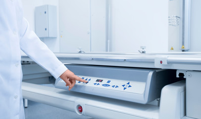 Doctor in medical gown starting X-ray machine