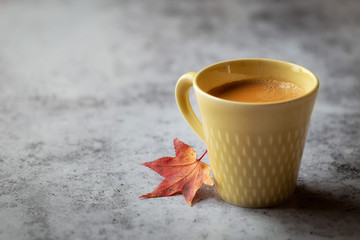 Autumn concept or fall time - a single cup of coffee with a red fallen leaf - obrazy, fototapety, plakaty