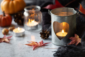 Autumn or fall concept with lit candles and autumnal leaves and fruits at the background.