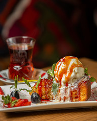 apple tarte topped with ice cream ball garnished with grape and strawberry