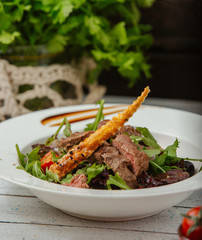 beef salad with arugula, tomatoes, and breadstick with sesame seeds