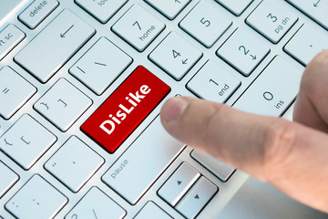 A dislike on keyboard button. A male finger presses a color button on a gray silver keyboard of a...