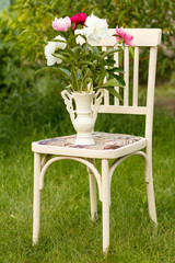 Vase of flowers on a white chair in the garden.