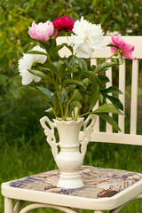 Vase of flowers on a white chair in the garden.