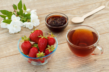 Glass cup of tea, strawberries with white jasmine flowers