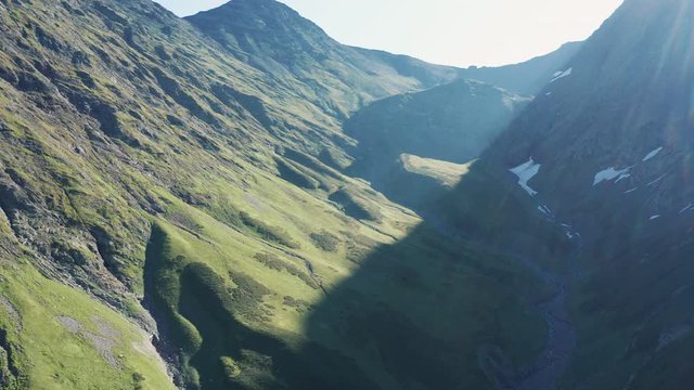 AERIAL ,4K; drone view of natural landscape with mountain riges, alpine steep slopes and valleys; early morning time; rocky cliffs and glasiers; beautiful panorama of summits, river with melting ice