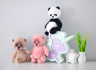 Three teddy bears are sitting on a chest of drawers.