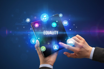 Businessman holding a foldable smartphone with EQUALITY inscription, social media concept