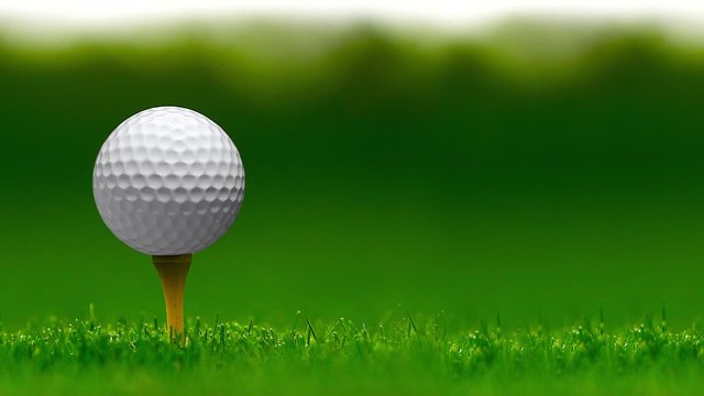 Unbranded golf ball spinning on a golf tee against a bokeh background - seamless looping.