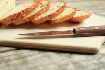  Fresh grain bread, sliced, lies on a wooden board. Nearby lies a knife.