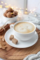 Cup of coffee, brown sugar, knitted scarf, garland. Autumn mood. Cozy autumn composition. Hygge concept. Soft focus