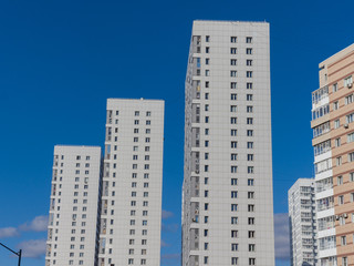 Fototapeta na wymiar New white high-rise residential buildings against the blue sky. The theme of an emerging housing market under construction