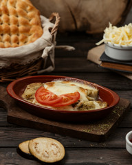 grilled aubergine topped with melted cheese and tomato slices on pottery pan 1