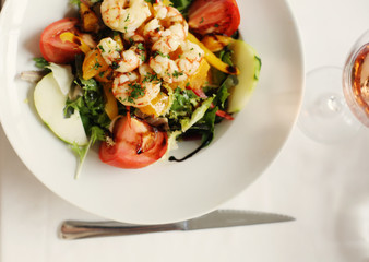Delicious fresh shrimp salad with grilled shrimps, greens, slices of tomatoes, pear, nuts dressed with balsamic vinegar and olive oil. Healthy food and diet. Perfect tasty lunch or brunch. Seafood.   