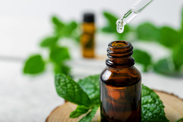 mint essential oil drop falling from dropper into the bottle