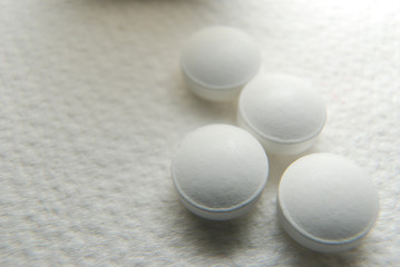 Fototapeta na wymiar Soft focus, white pills scattered on a white background