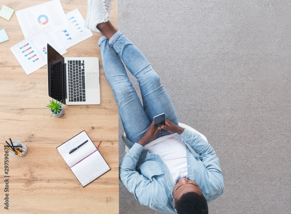 Poster careless worker using smartphone and keeping his legs on table