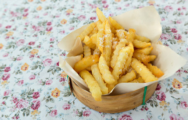 Fried French fries on a plate on the wooden table. Yummy french fries as background. French fries in a bowl on a wooden background.