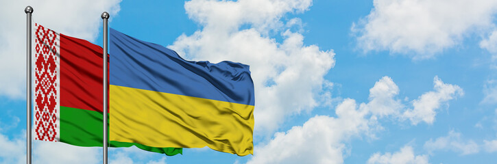 Belarus and Ukraine flag waving in the wind against white cloudy blue sky together. Diplomacy concept, international relations.