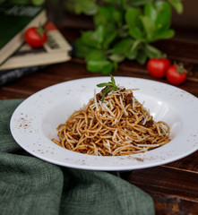 minced meat spaghetti garnished with grated parmesan in white plate