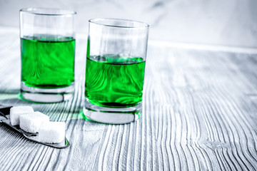 absinthe with sugar cubes and spoon on wooden background
