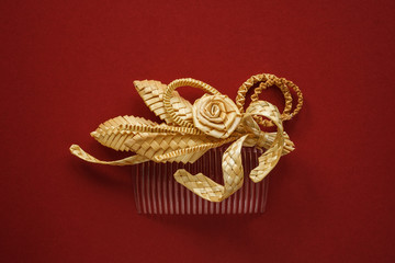 Ornamental hair comb with straw flowers on a red background
