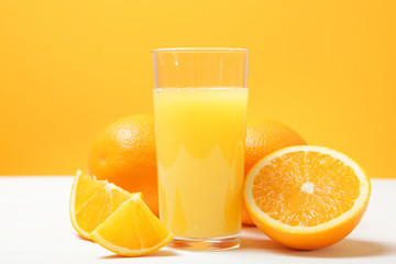 Orange juice in a glass, oranges and orange slices on the table.